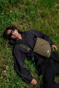 Model laying in the grass with FFUJJI Portra Bag in green colorway, enjoying the sunshine.