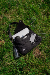 FFUJJI Portra Bag laying in grass with Macbook, IPhone and Water flask.